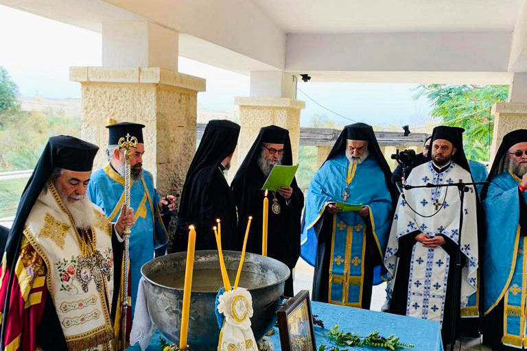 A group of religious leaders participating in a ceremony stand around an alter at the baptism site