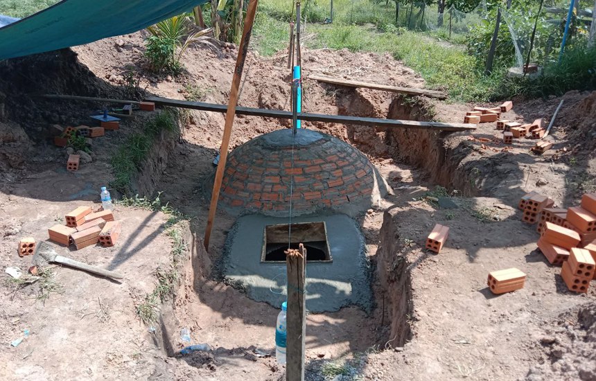 Bricks lay around the nearly complete Biogas Digester 