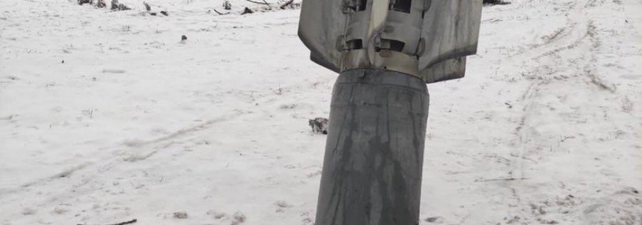 An unexploded ordinance sits half buried into the snowy ground