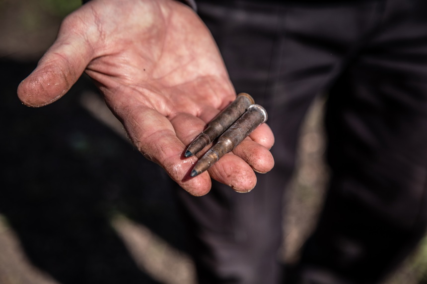 A close up of a hand holding two bullets
