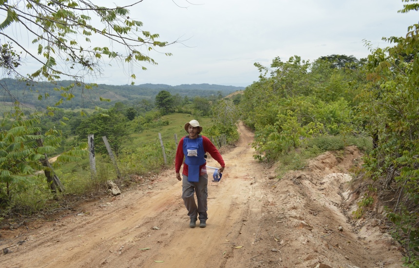 A HALO staff member wearing PPE walks through a small dirt track