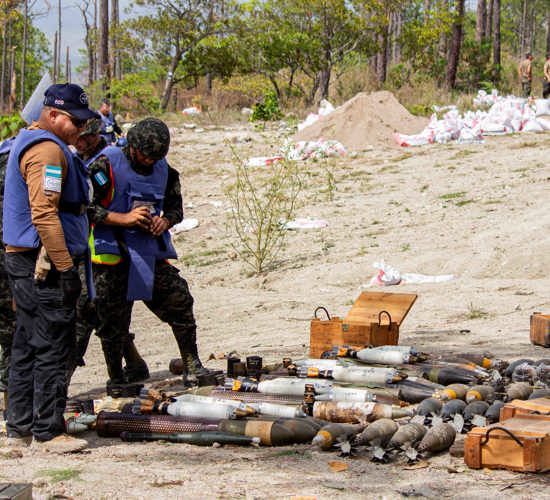 People in HALO vests gather round a stockpile of weapons in Honduras