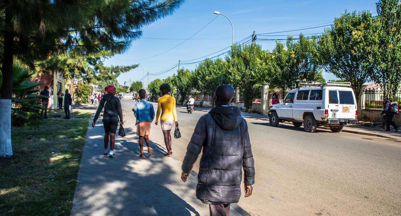 People walking along a tree-lined street in Huambo