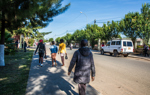 People walking along a tree-lined street in Huambo