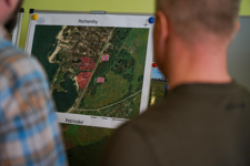 Two men look at a map of the petriviske region with Norway flags on it