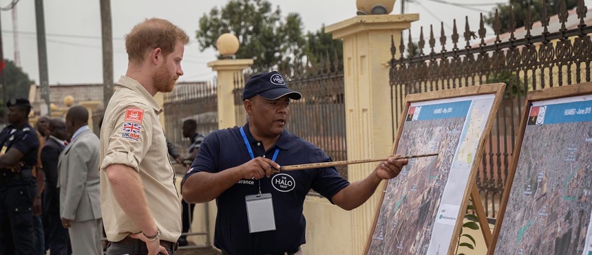Prince Harry receives a briefing from a HALO staff member pointing at a map of Huambo, Angola