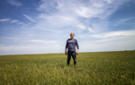 A man in sunglasses stands in the middle of a green field.