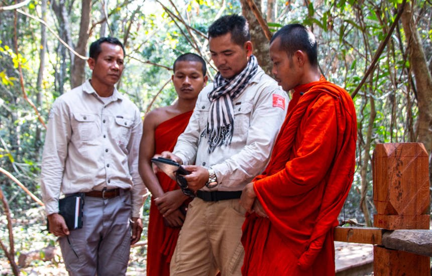 HALO staff discussing mine clearance with two monks