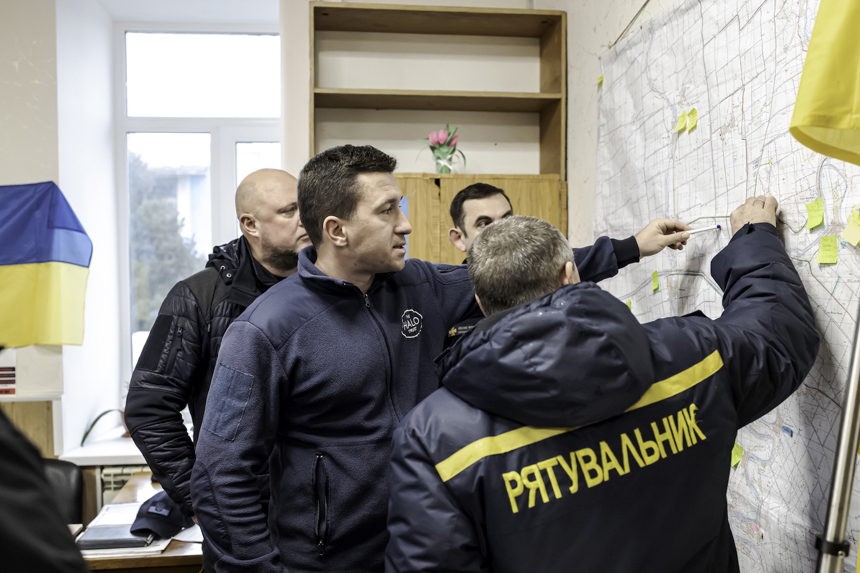 In an office, staff members point to a map on the wall as they make plans