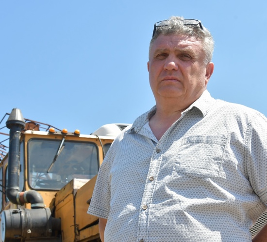 Serhii Kishkovskyi, a Ukrainian farmer stands in front of his farming vehicle in a field