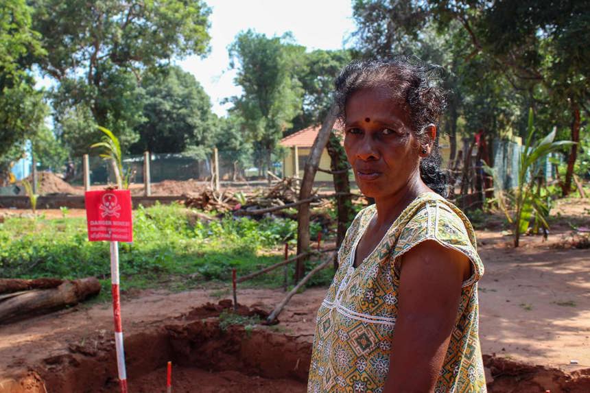 Kirubayrani stands next to a landmine sign outside
