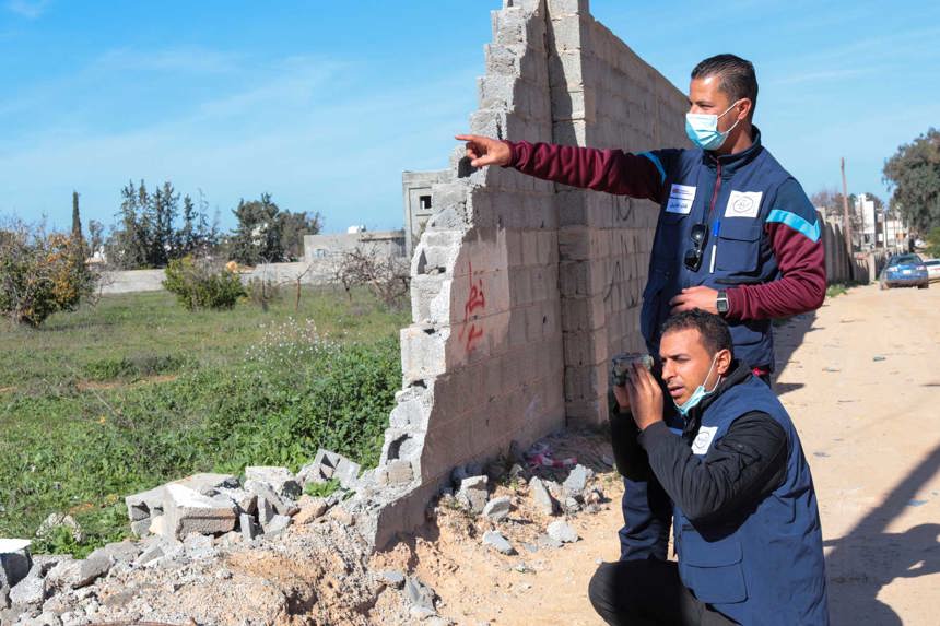 Two members from the survey team point and use binoculars to look into the field