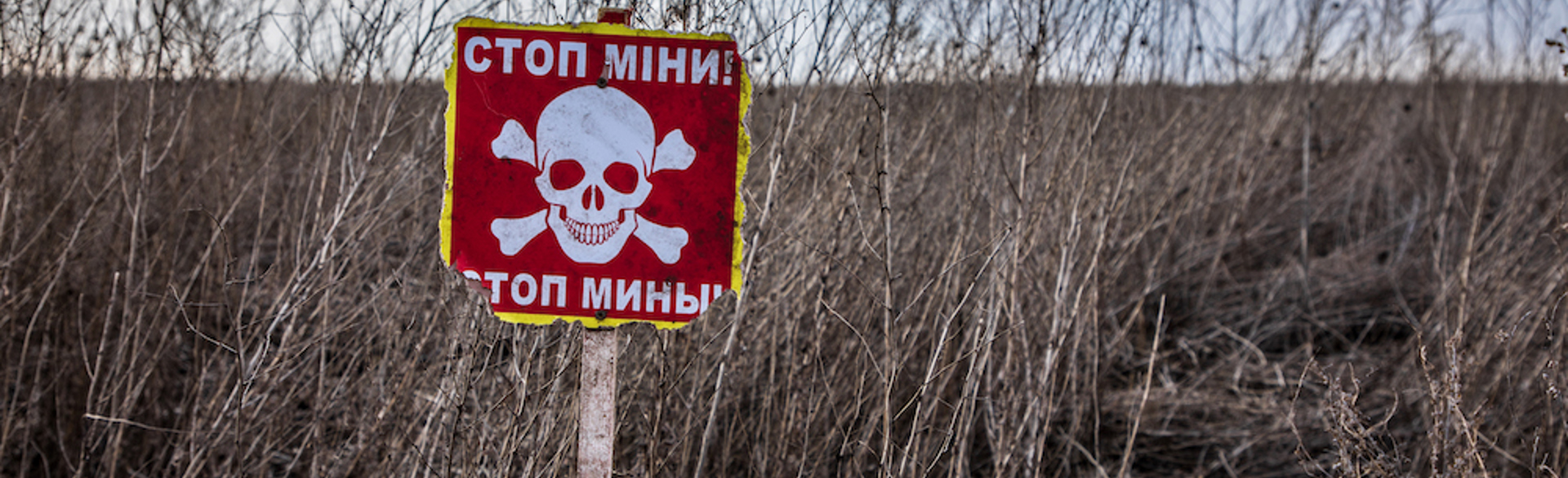 A red danger mine sign stands in a farmers field in the kharkiv region