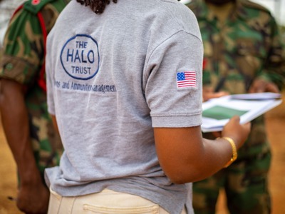 HALO staff member holds some papers and faces military personnel