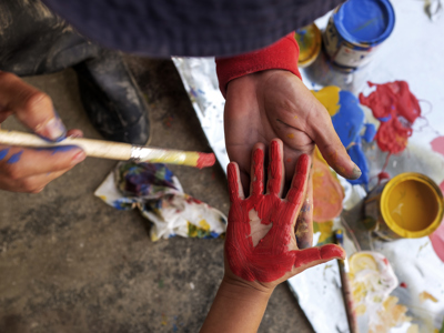 A child's hand painted red to print onto the school wall