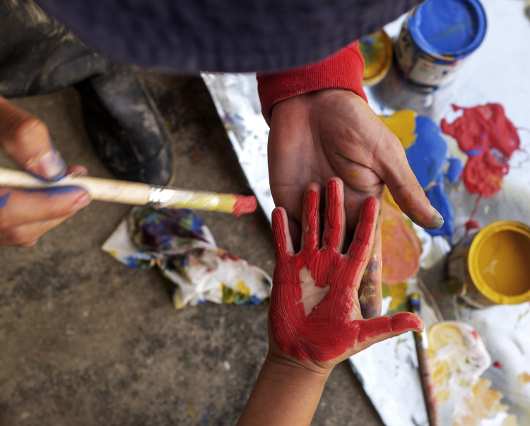 A child's hand painted red to print onto the school wall