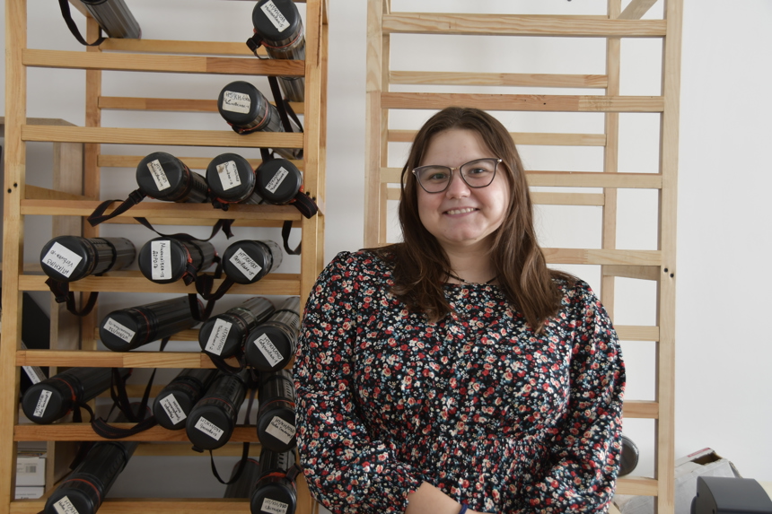 Liza stands in front of her shelf storage of maps
