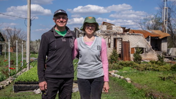 Natalia and Vyacheslav, a couple from Kharkiv, stand with their arms linked in their backyard 