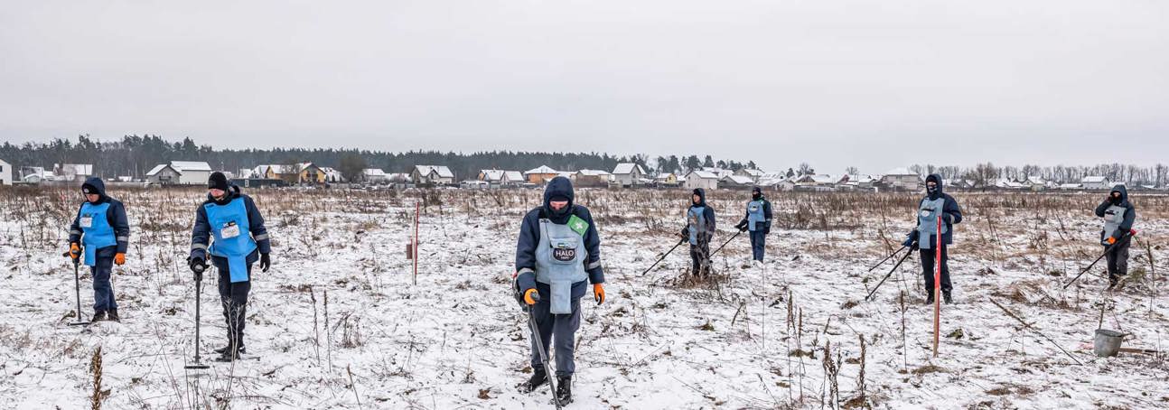 A team of HALO deminers work in a snow-covered minefield using metal detectors in Ukraine