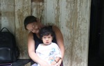 A woman sits and smiles with her baby on her lap