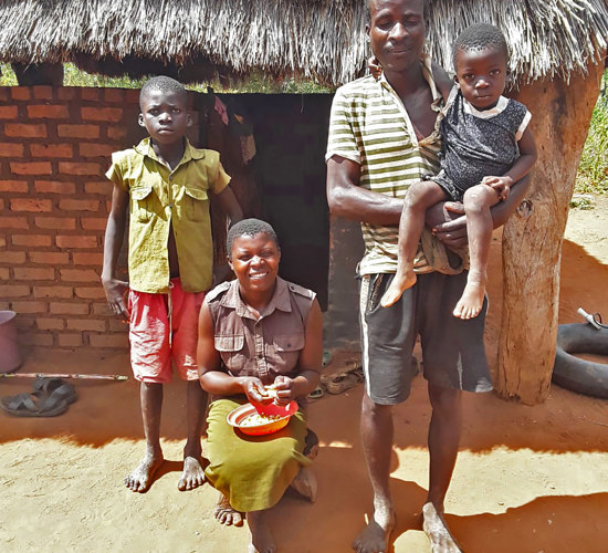 Godfrey and his family outside of their home in Zimbabwe
