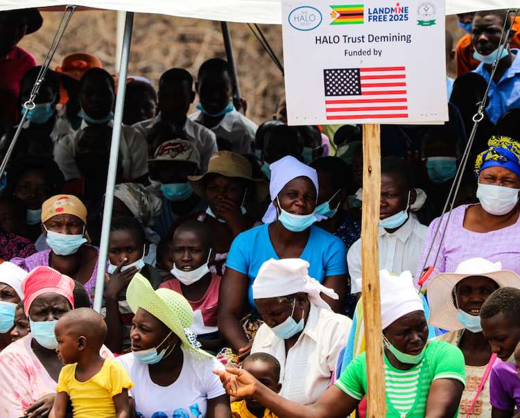 Locals gather together with a US funded landmine free sign