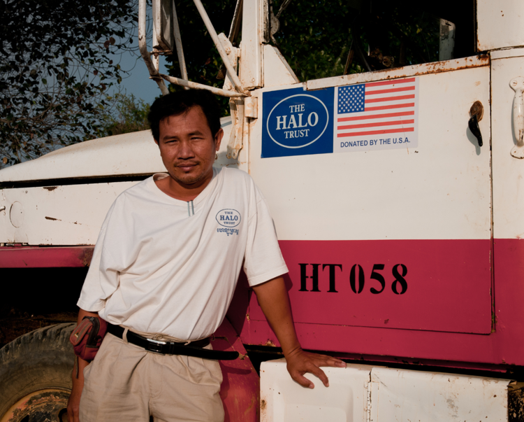 A HALO staff member poses in front of a US badged HALO truck