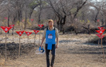 Prince Harry walks through a minefield in Angola, wearing PPE and holding a visor next to red danger signs