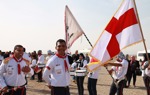 Pilgrims walk through the Baptism Site waving flags and smiling