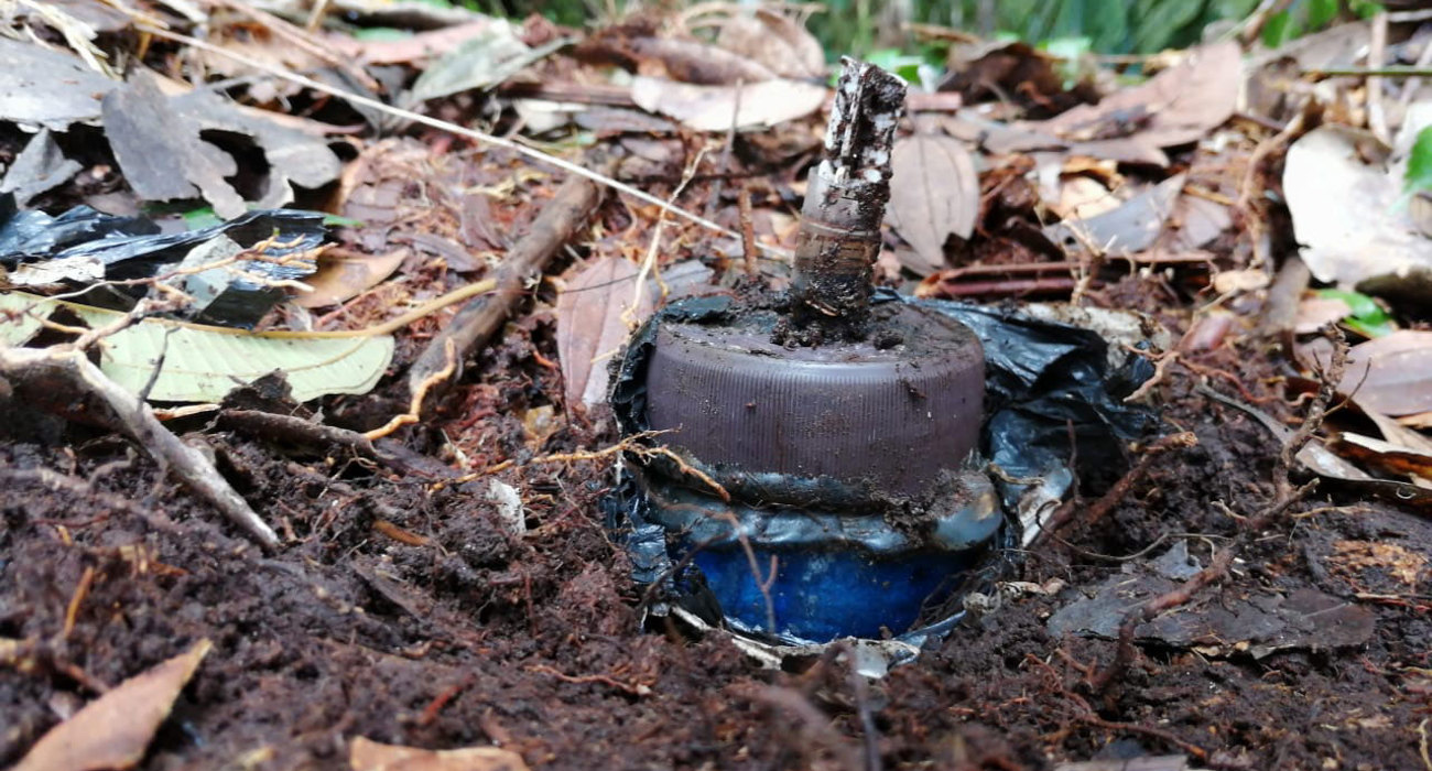 A close up of a landmine half buried in the ground