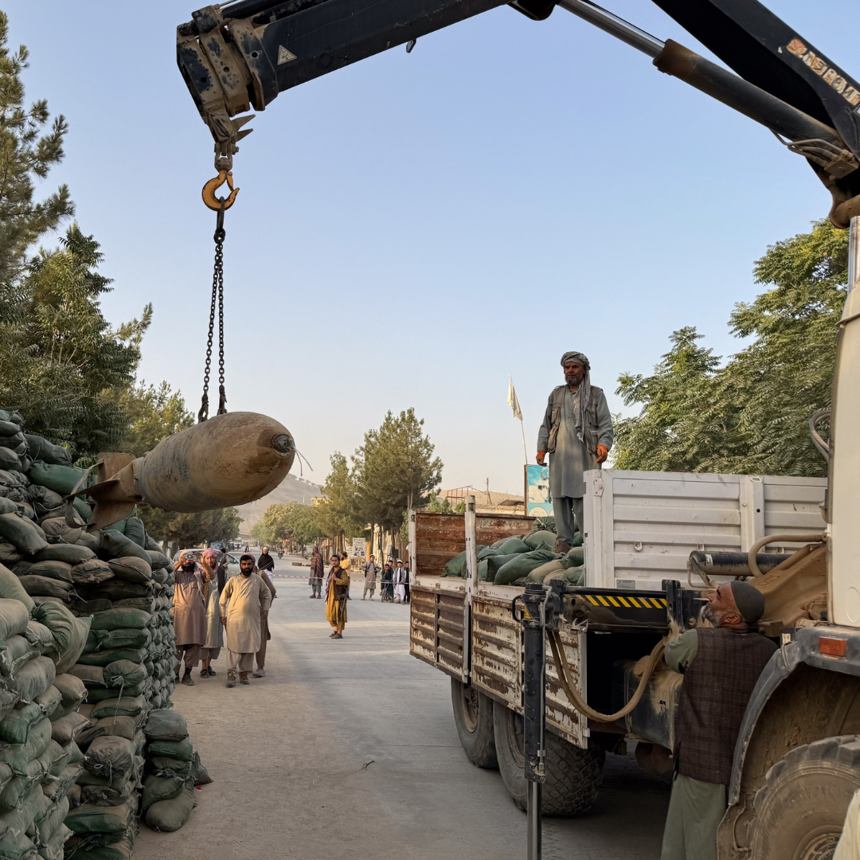 A group of people moving large bombs onto a truck