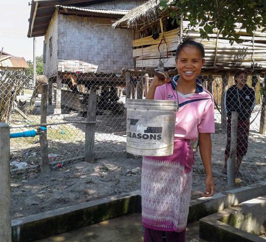 Ms Nouy, from Tamlouang village, holds a bucket of water next to a tap