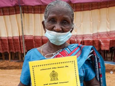 A woman stands outside holding a yellow booklet