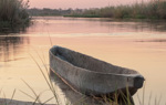 A carved wooden canoe on the Cuito river during sunset